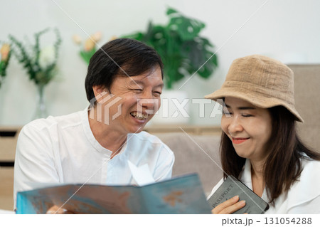 Senior couple planning travel itinerary together, sharing joy and excitement over trip details. 131054288