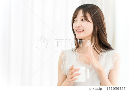朝,家で白湯,コーヒー,ホットドリンクを飲む笑顔のアジア人女性(おはよう,手を振る) 朝,家で白湯,コーヒー,ホットドリンクを飲む笑顔のアジア人女性(おはよう,手を振る) 131056525