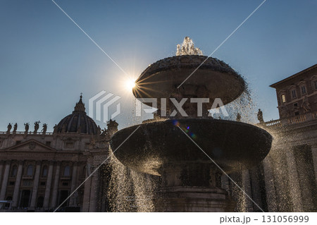 Fountain in St. Peter's Square with the sun shining dramatically through water streams, Vatican City landmark at sunrise 131056999