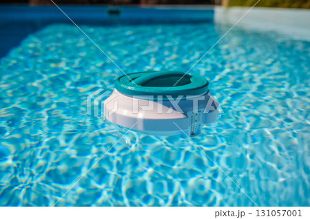Floating chlorine dispenser with thermometer drifting on pool water, ensuring effective disinfection and proper maintenance of swimming pool hygiene Floating chlorine dispenser with thermometer drifting on pool water, ensuring effective disinfection and proper maintenance of swimming pool hygiene 131057001