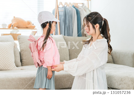 自宅のリビングで娘の着替えを手伝う母親 131057236
