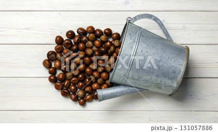 Spilled chestnuts from a metal bucket on wooden surface during autumn harvest season 131057886
