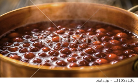 Cooking a pot of rich, red cranberry sauce on a warm stove with steam rising 131058136