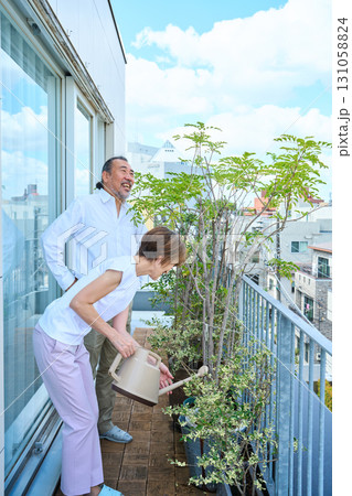 ベランダで観葉植物に水をあげる熟年夫婦　資産家 131058824