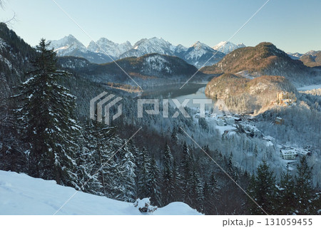Snowy Mountain Landscape with Iconic Castle Overlooking Serene Lake and Alpine Peaks in Ethereal Winter Wonderland Bathed in Soft Dawn Light Snowy Mountain Landscape with Iconic Castle Overlooking Serene Lake and Alpine Peaks in Ethereal Winter Wonderland Bathed in Soft Dawn Light 131059455