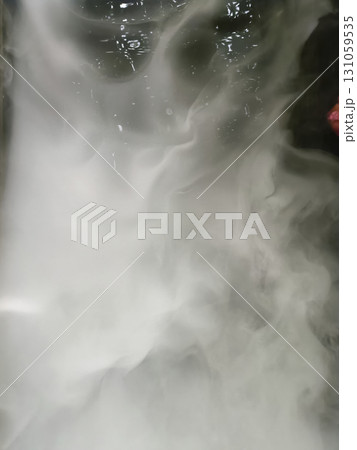 Image shows swirling white smoke or vapor with dark background, creating mysterious and ethereal atmosphere. smoke appears dense and flowing, with some reflections visible on surface Image shows swirling white smoke or vapor with dark background, creating mysterious and ethereal atmosphere. smoke appears dense and flowing, with some reflections visible on surface 131059535