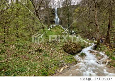 Cascading Waterfall in Lush Forest with Moss-Covered Rocks, Fast-Moving Stream, Wooden Bridge, Serene and Picturesque Atmosphere. Cascading Waterfall in Lush Forest with Moss-Covered Rocks, Fast-Moving Stream, Wooden Bridge, Serene and Picturesque Atmosphere. 131059537