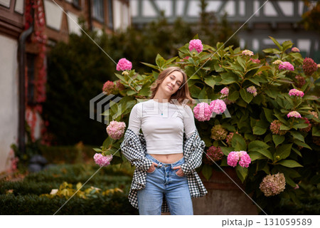 Autumn Fashion Portrait: Stylish Woman Amidst Blooming Hydrangeas at Traditional German Half Timbered House. Cozy Fall Outdoor Scene Showcasing Casual Outfit and Warm Colors in Picturesque Rural Autumn Fashion Portrait: Stylish Woman Amidst Blooming Hydrangeas at Traditional German Half Timbered House. Cozy Fall Outdoor Scene Showcasing Casual Outfit and Warm Colors in Picturesque Rural 131059589