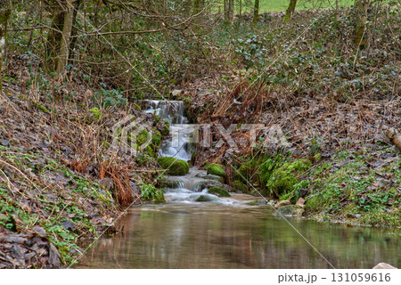 Enchanting Forest Waterfall: Cascading Mountain Stream with Autumn Foliage and Golden Sunset Light. Long Exposure Captures Silky Water Flow Over Moss Covered Rocks in Lush Green Woodland 131059616