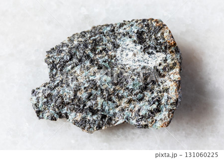 sample of rough gabbro-norite rock on white marble 131060225