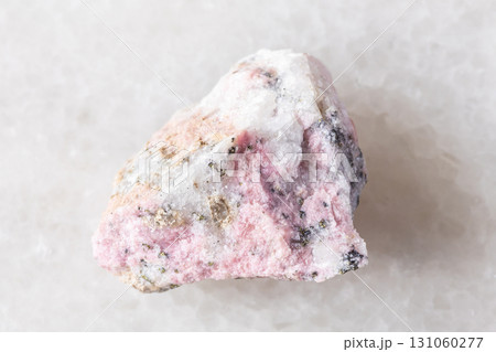 sample of raw pyroxmangite rock on white marble 131060277
