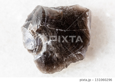 sample of raw obsidian rock on white marble 131060296