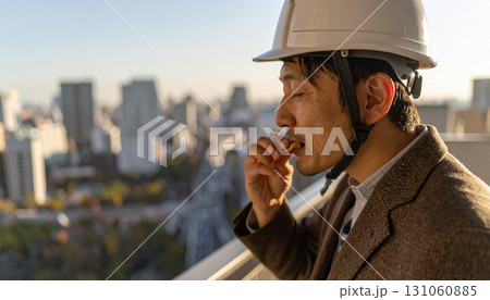Asian Construction Worker Eating Food on Building Rooftop 131060885