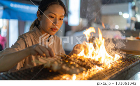 Female Chef Grilling Chicken Yakitori Over Open Flames 131061042