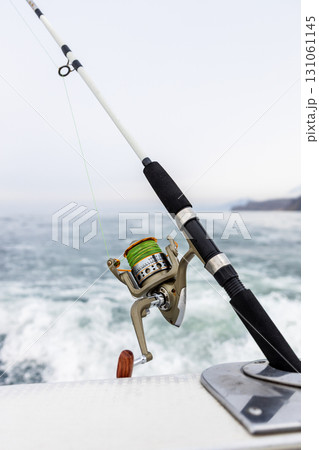 spinning reel closeup on fishing rod on stern 131061145
