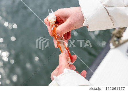 tourist opens leg of freshly caught crab on boat 131061177