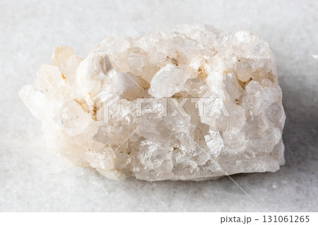 rough druse of clear quartz rock on white marble 131061265