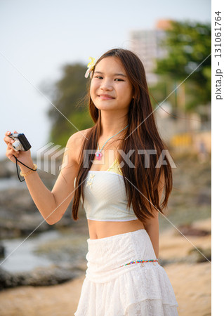 A teenage woman in a white dress is enjoying her vacation on the beach 131061764