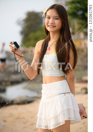 A teenage woman in a white dress is enjoying her vacation on the beach A teenage woman in a white dress is enjoying her vacation on the beach 131061765