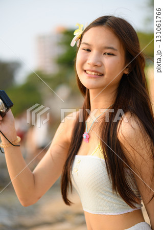 A teenage woman in a white dress is enjoying her vacation on the beach 131061766