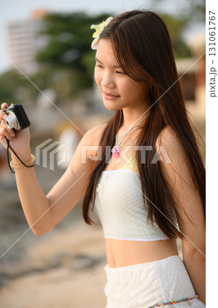 A teenage woman in a white dress is enjoying her vacation on the beach A teenage woman in a white dress is enjoying her vacation on the beach 131061767
