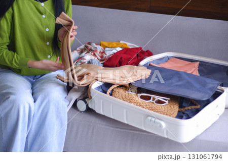 Young women folding clothes, packing luggage for holiday trip.    131061794