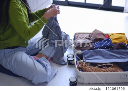 Young women folding clothes, packing luggage for holiday trip. Young women folding clothes, packing luggage for holiday trip. 131061796