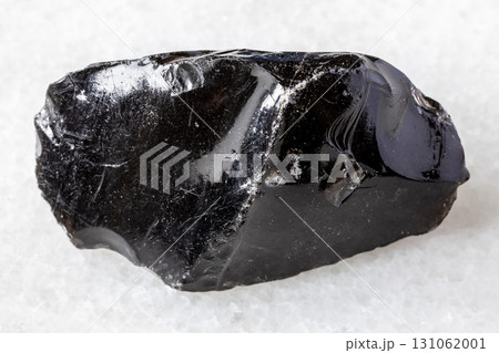 sample of raw obsidian mineral on white marble 131062001