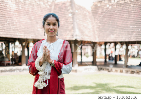 Woman in traditional attire performing a respectful greeting in a historic courtyard, showcasing cultural heritage. 131062316