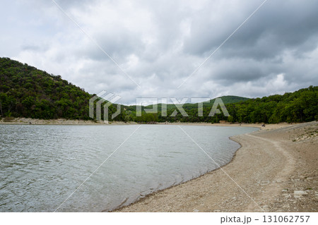Mountain lake with cypress trees in cloudy weather 131062757