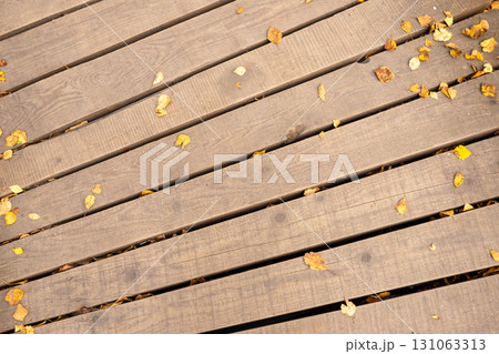 Wooden plank path, decking, eco-trail turns left with autumn yellow leaves. Top view, full frame Wooden plank path, decking, eco-trail turns left with autumn yellow leaves. Top view, full frame 131063313