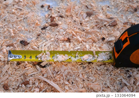 Tape measure retracting on sawdust covered surface of woodworking plant. Tape measure retracting on sawdust covered surface of woodworking plant. 131064094