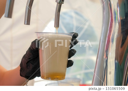 Bartender pouring beer into plastic cup montage 131065509