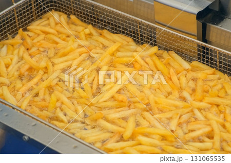 Crispy french fries cooking frying to golden perfection in a deep fryer on street. Crispy french fries cooking frying to golden perfection in a deep fryer on street. 131065535