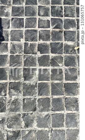 Close up view of cobblestone pavement with small, square stones arranged in grid pattern, showing texture and natural stone variations Close up view of cobblestone pavement with small, square stones arranged in grid pattern, showing texture and natural stone variations 131065757