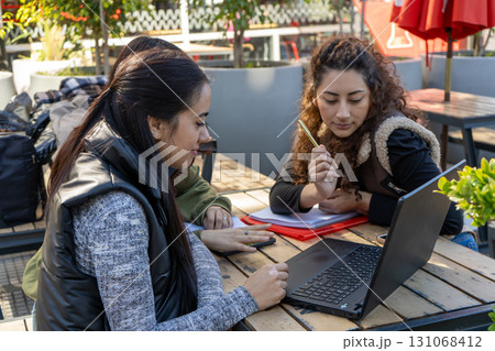 University students collaborating on project outdoors with laptop and notebook University students collaborating on project outdoors with laptop and notebook 131068412