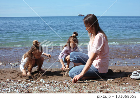 mother with twins daughters on beach 131068658