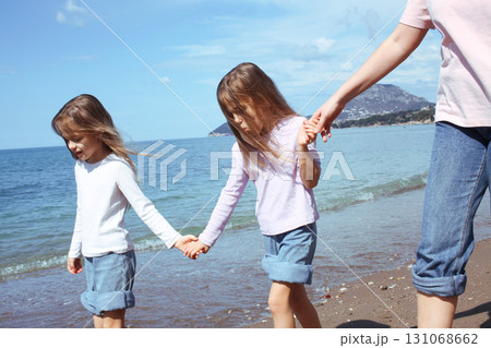 mother with twins daughters on beach 131068662