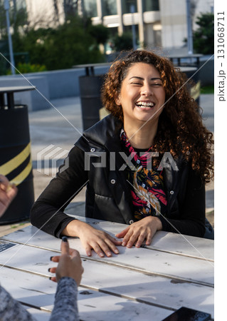 Young woman laughing while talking with friend outdoors 131068711