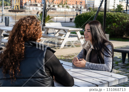 Two young women talking and smiling at outdoor table in buenos aires 131068713