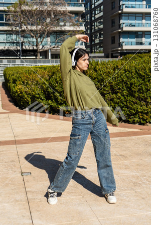Young woman dancing with headphones in urban park Young woman dancing with headphones in urban park 131068760
