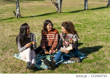 Three latin girls having fun and enjoying a picnic in the park Three latin girls having fun and enjoying a picnic in the park 131068782