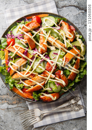 Buffalo chicken salad, featuring spicy chicken, crisp lettuce, vegetables and a creamy blue cheese dressing closeup on the plate. Vertical top view 131068808