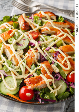 Buffalo chicken salad, featuring spicy chicken, crisp lettuce, vegetables and a creamy blue cheese dressing closeup on the plate. Vertical 131068814