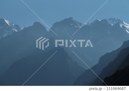 Silhouettes of snow-capped mountains and low clouds at dawn 131069087