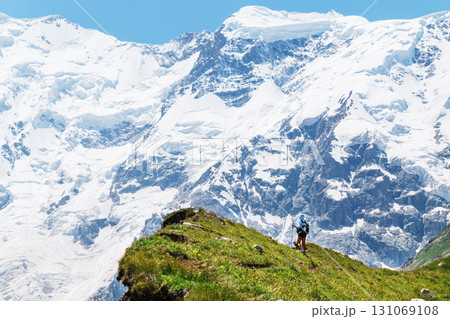 A traveler at a very high altitude with a view of the long tongue of the glacier and high snowy mountains 131069108