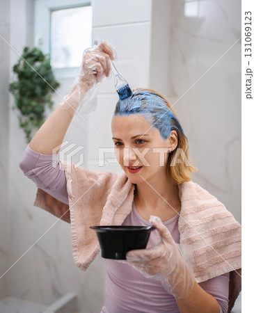 Woman dyeing her hair blue in the bathroom 131069123
