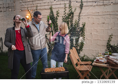 Friends celebrate outdoors with a barbecue and laughter in the evening glow 131069139