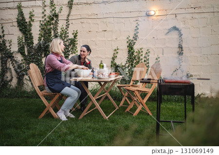 Friends enjoying a barbecue in a cozy garden at sunset Friends enjoying a barbecue in a cozy garden at sunset 131069149