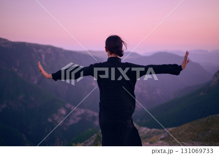 Woman practicing Tai Chi in traditional black outfit on mountain at sunrise, arms outstretched in meditation pose focusing on balance, energy, and mindfulness in nature. Woman practicing Tai Chi in traditional black outfit on mountain at sunrise, arms outstretched in meditation pose focusing on balance, energy, and mindfulness in nature. 131069733